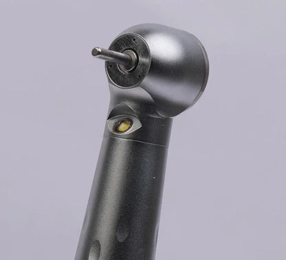 Close-up of a dental airotor handpiece with bur, black and metallic finish, on gray background