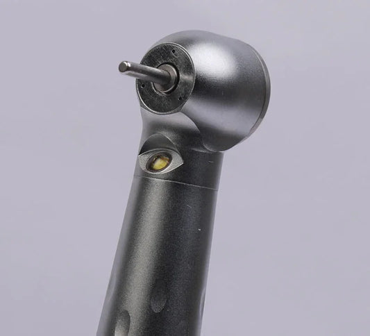 Close-up of a dental airotor handpiece with bur, black and metallic finish, on gray background